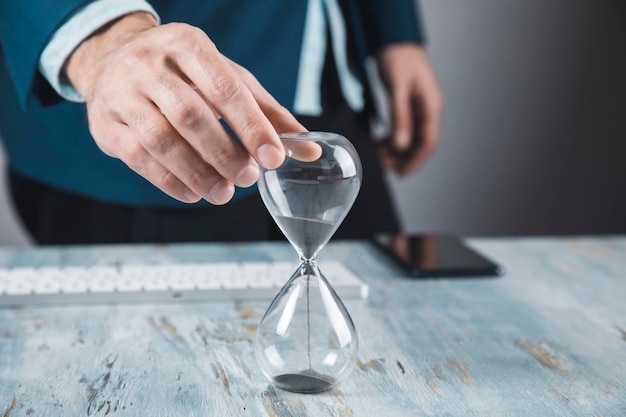 Foto joven empresario sosteniendo reloj de arena en la mano