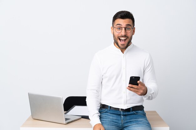 Joven empresario sosteniendo un teléfono móvil con expresión facial sorpresa