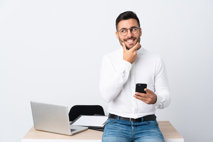 Foto joven empresario sosteniendo un teléfono móvil pensando en una idea