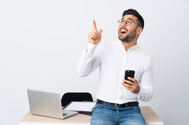 Joven empresario sosteniendo un teléfono móvil señalando con el dedo índice una gran idea