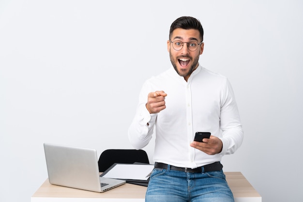 Joven empresario sosteniendo un teléfono móvil te señala con el dedo