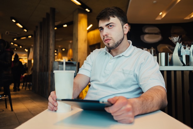 Joven empresario con tableta en un café