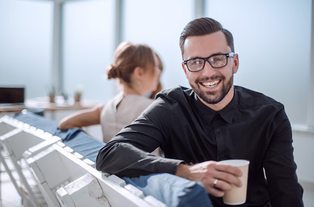 Foto joven empresario con una taza de café sentado en una oficina moderna