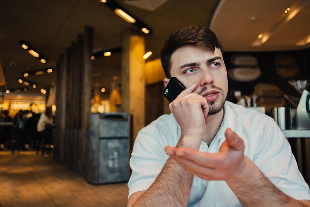 Joven empresario mediante teléfono móvil en un café