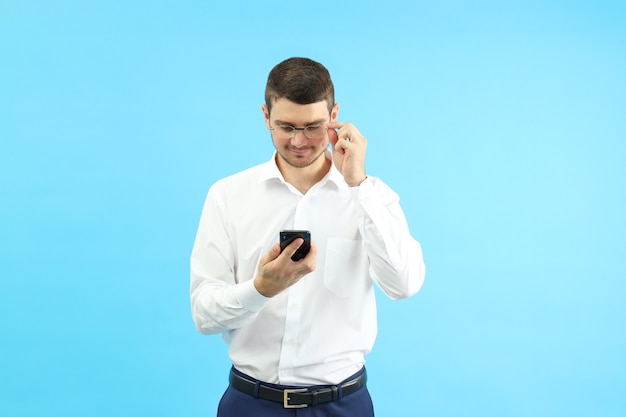 Joven empresario con teléfono sobre fondo azul.