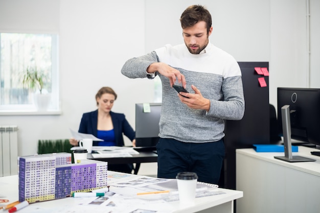 Un joven empresario tomando fotos del proyecto de construcción mientras estaba en la oficina