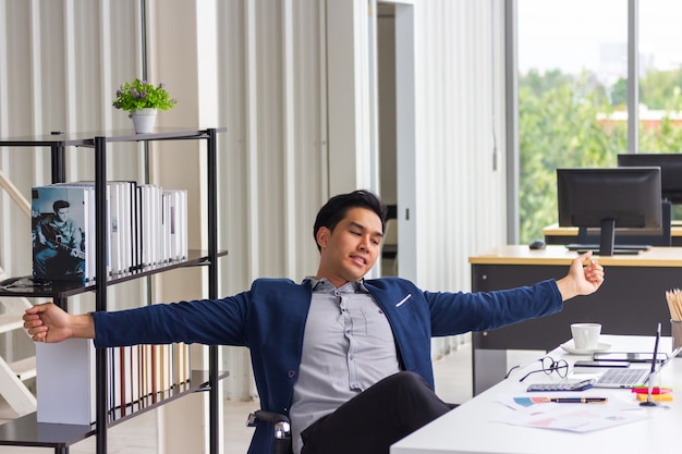 Joven empresario trabajador tomando un descanso en el trabajo relajante sentado en una silla ergonómica en el escritorio de la oficina descansando trabajo de computadora terminado encontró la solución con el trabajo bien hecho