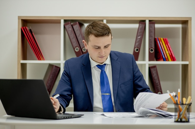 Joven empresario trabajando con documentos mirando documentos en carpeta