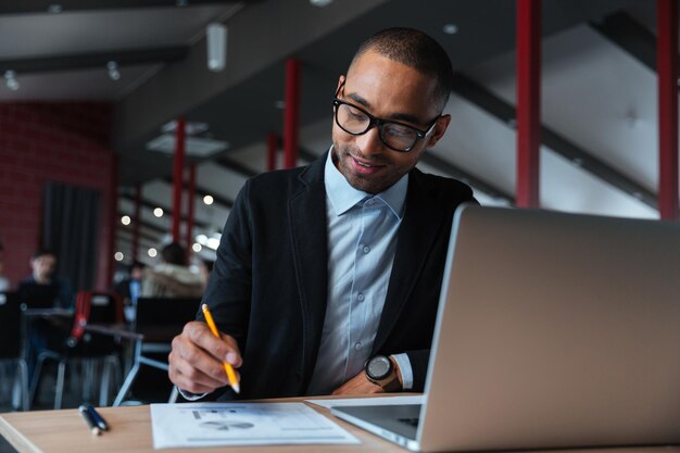 Joven empresario trabajando con un portátil y escribiendo notas en la oficina