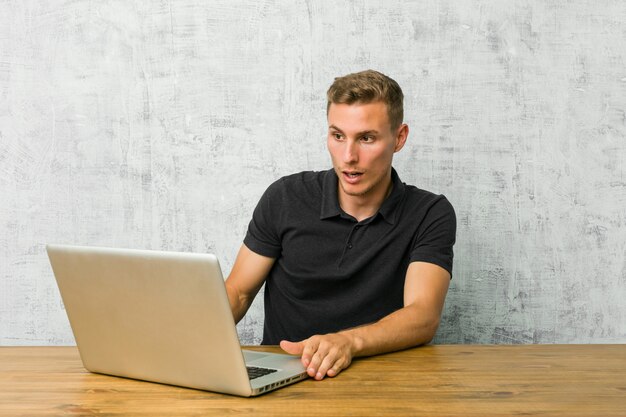 Joven empresario trabajando con su computadora portátil en un escritorio sorprendida por algo que ella ha visto.