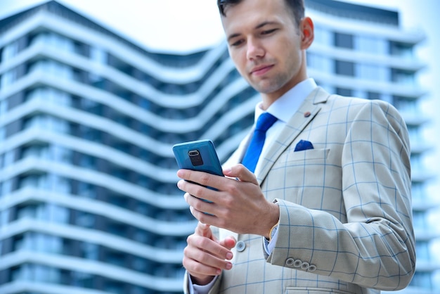 Joven empresario de traje con smartphone en la mano