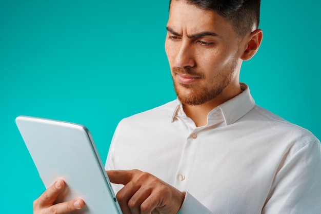 Joven empresario vistiendo camisa blanca tiene tableta digital contra fondo verde