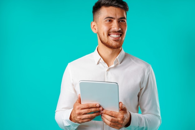 Joven empresario vistiendo camisa blanca tiene tableta digital contra verde
