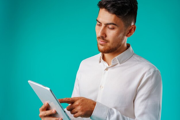 Joven empresario vistiendo camisa blanca tiene tableta digital