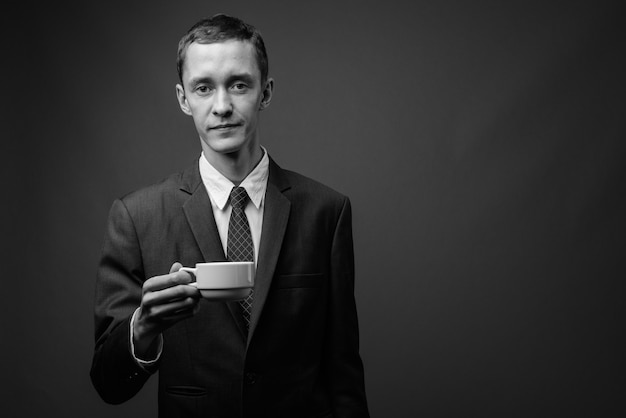 Joven empresario vistiendo traje contra la pared gris en blanco y negro