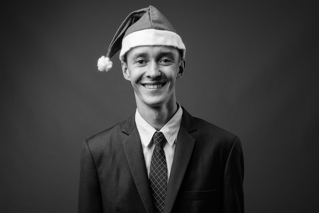 Joven empresario vistiendo traje contra la pared gris en blanco y negro