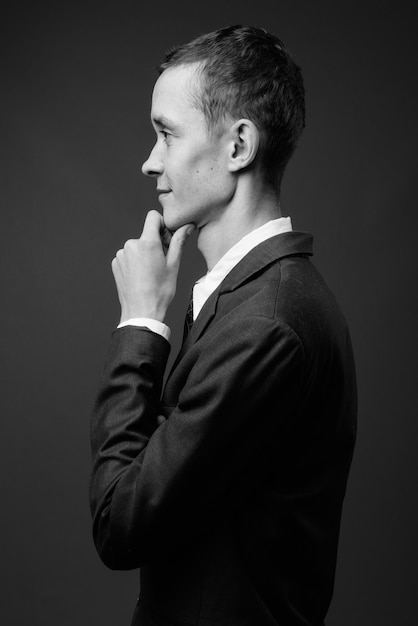 Joven empresario vistiendo traje contra la pared gris en blanco y negro