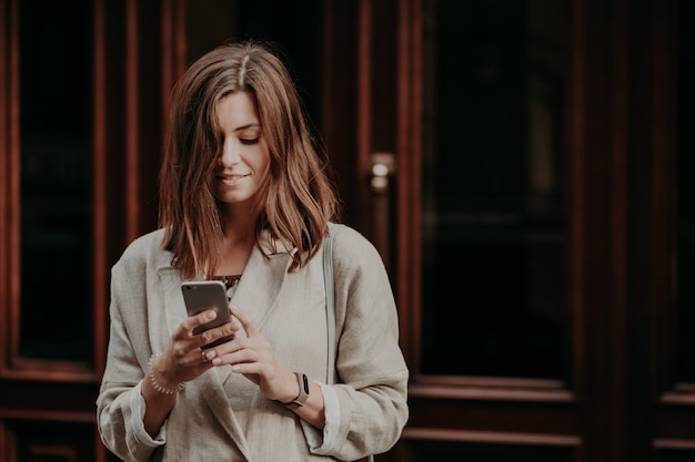 La joven encantada contenta ve un video en un teléfono inteligente