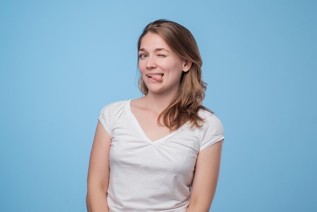 Una joven encantadora con una camiseta blanca mostrando la lengua