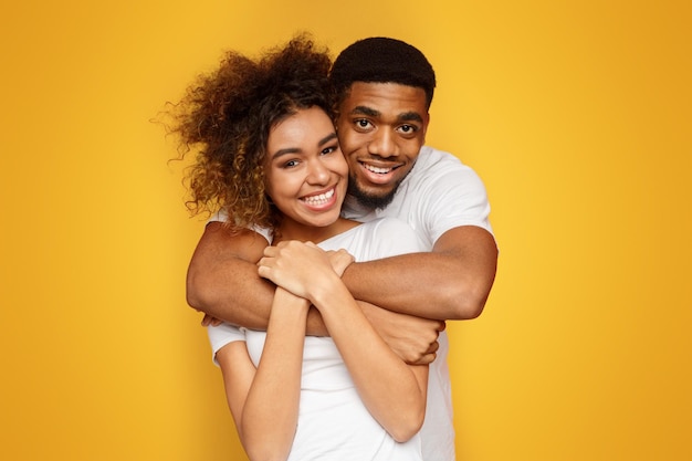 Una joven y encantadora pareja afroamericana posando sobre un fondo naranja