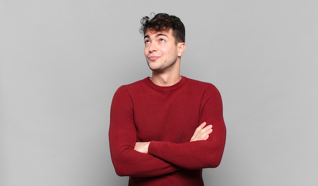 Joven encogiéndose de hombros, sintiéndose confuso e inseguro, dudando con los brazos cruzados y la mirada perpleja