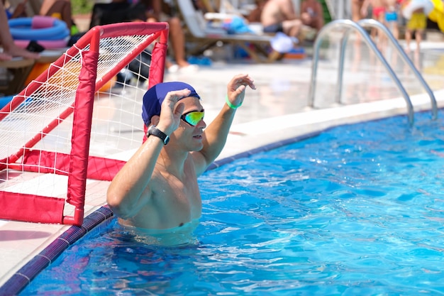 Joven se encuentra en la puerta en la piscina jugando waterpolo closeup