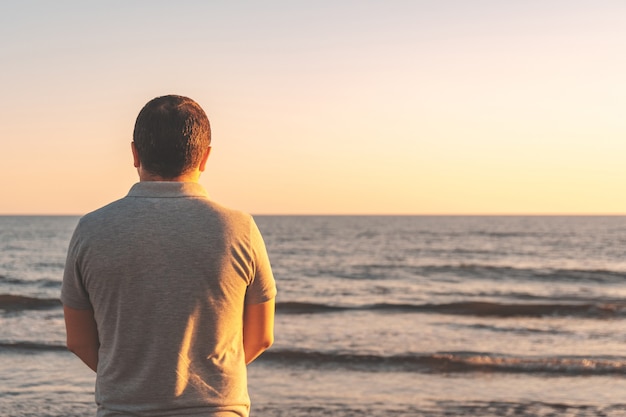 Joven se encuentra con la puesta de sol en la playa en el mar, por la noche