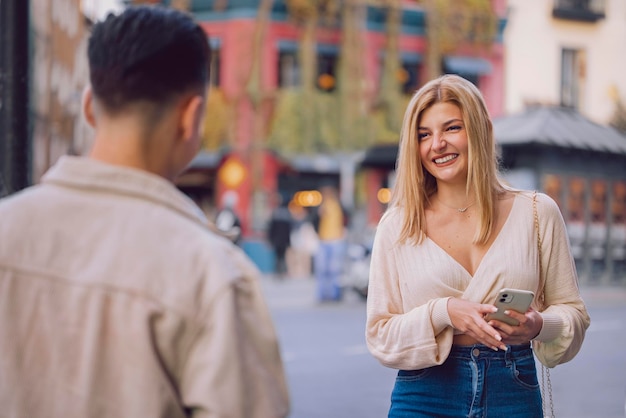 Una joven se encuentra con su cita en la ciudad mientras sostiene su teléfono