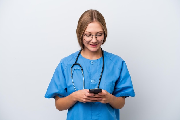 Joven enfermera doctora aislada de fondo blanco enviando un mensaje con el móvil