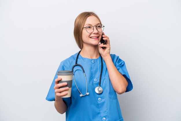 Joven enfermera doctora aislada de fondo blanco sosteniendo café para llevar y un móvil