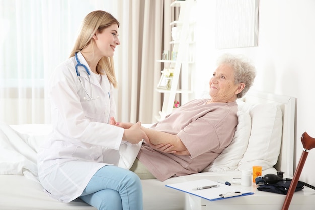 Joven enfermera examinando a anciana en casa