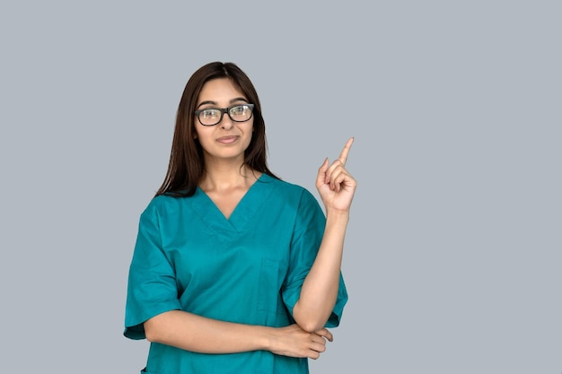 Una joven enfermera india sonriente apunta al espacio de copia aislado sobre un fondo gris