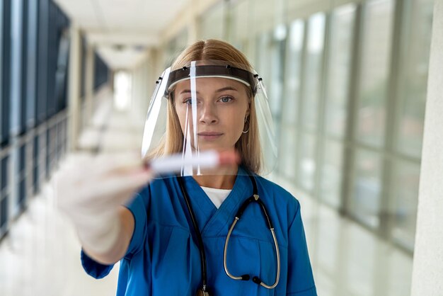 Joven enfermera se para en el pasillo y realiza una prueba de coronavirus