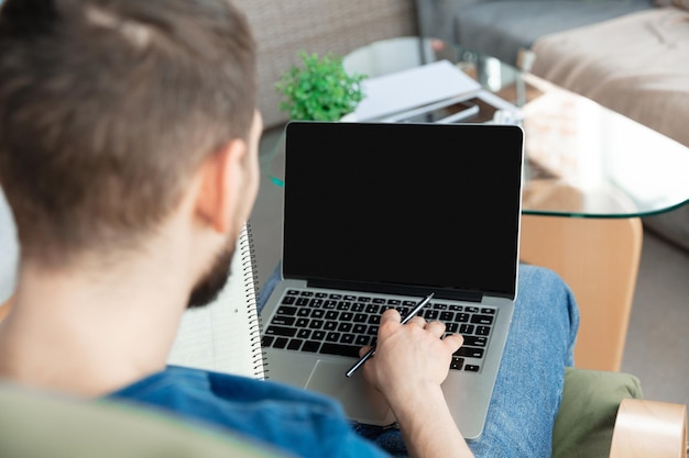 Joven enfocado estudiando en casa durante cursos en línea o información gratuita por sí mismo