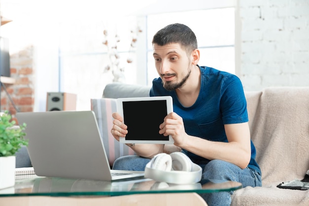 Joven enfocado estudiando en casa durante cursos en línea o información gratuita por sí mismo