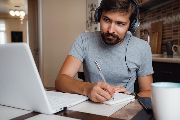 El joven enfocado usa auriculares para estudiar en línea