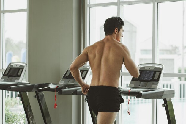 Joven en entrenamiento corriendo en el gimnasio de la caminadora en casa