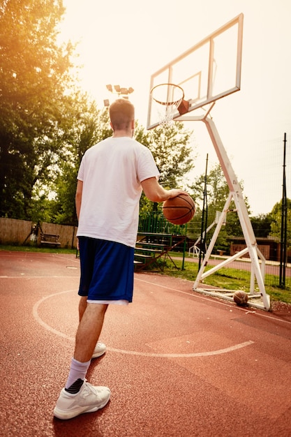 Joven entrenando baloncesto en la cancha de la calle. Él está listo para disparar.