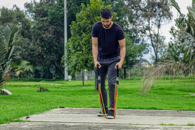 joven entrenando con bandas elásticas haciendo ejercicio de brazos al aire libre en un parque