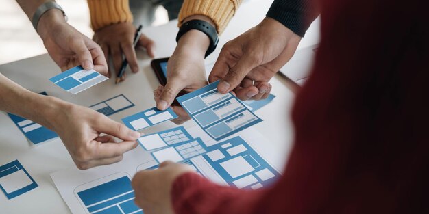 Joven equipo creativo de negocios asiáticos trabajan juntos proyecto de diseño de software de aplicaciones móviles reunión de lluvia de ideas tecnología de Internet teléfono inteligente diseñador de aplicaciones web oficina compañero de trabajo concepto de trabajo en equipo