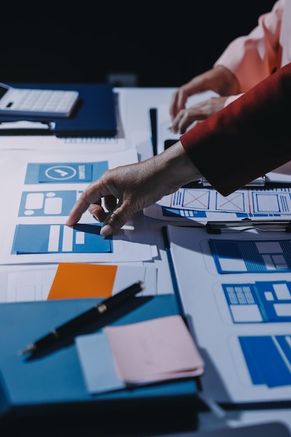 Joven equipo creativo de negocios asiáticos trabajan juntos proyecto de diseño de software de aplicaciones móviles reunión de lluvia de ideas tecnología de Internet teléfono inteligente diseñador de aplicaciones web oficina compañero de trabajo concepto de trabajo en equipo