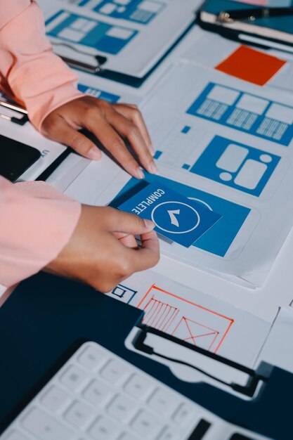 Joven equipo creativo de negocios asiáticos trabajan juntos proyecto de diseño de software de aplicaciones móviles reunión de lluvia de ideas tecnología de Internet teléfono inteligente diseñador de aplicaciones web oficina compañero de trabajo concepto de trabajo en equipo