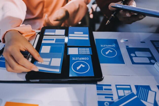 Joven equipo creativo de negocios asiáticos trabajan juntos proyecto de diseño de software de aplicaciones móviles reunión de lluvia de ideas tecnología de Internet teléfono inteligente diseñador de aplicaciones web oficina compañero de trabajo concepto de trabajo en equipo