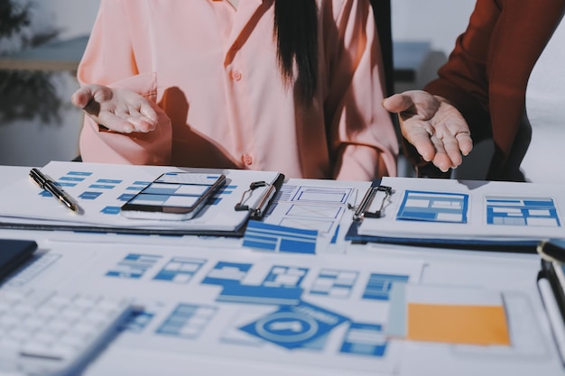 Joven equipo creativo de negocios asiáticos trabajan juntos proyecto de diseño de software de aplicaciones móviles reunión de lluvia de ideas tecnología de Internet teléfono inteligente diseñador de aplicaciones web oficina compañero de trabajo concepto de trabajo en equipo