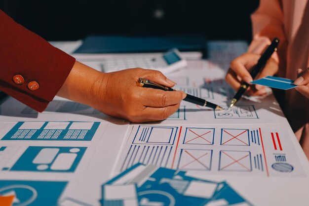 Joven equipo creativo de negocios asiáticos trabajan juntos proyecto de diseño de software de aplicaciones móviles reunión de lluvia de ideas tecnología de Internet teléfono inteligente diseñador de aplicaciones web oficina compañero de trabajo concepto de trabajo en equipo