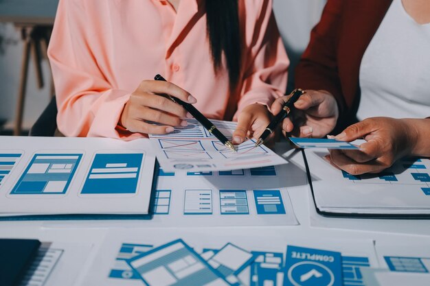 Joven equipo creativo de negocios asiáticos trabajan juntos proyecto de diseño de software de aplicaciones móviles reunión de lluvia de ideas tecnología de Internet teléfono inteligente diseñador de aplicaciones web oficina compañero de trabajo concepto de trabajo en equipo