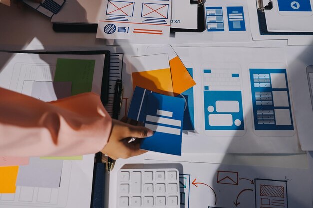 Joven equipo creativo de negocios asiáticos trabajan juntos proyecto de diseño de software de aplicaciones móviles reunión de lluvia de ideas tecnología de Internet teléfono inteligente diseñador de aplicaciones web oficina compañero de trabajo concepto de trabajo en equipo