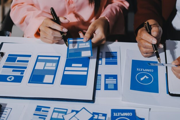 Joven equipo creativo de negocios asiáticos trabajan juntos proyecto de diseño de software de aplicaciones móviles reunión de lluvia de ideas tecnología de Internet teléfono inteligente diseñador de aplicaciones web oficina compañero de trabajo concepto de trabajo en equipo