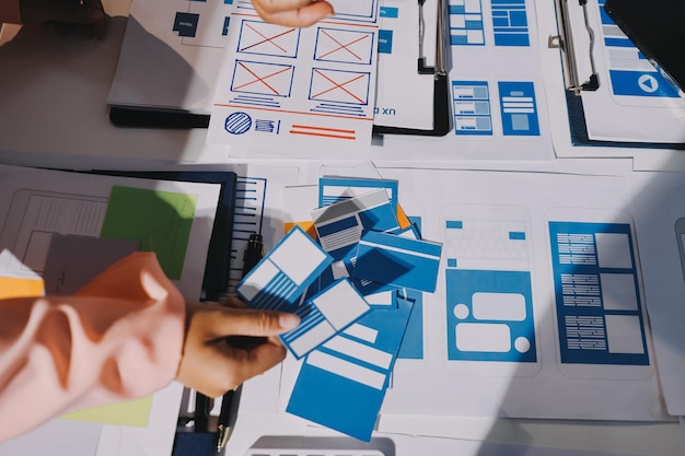 Joven equipo creativo de negocios asiáticos trabajan juntos proyecto de diseño de software de aplicaciones móviles reunión de lluvia de ideas tecnología de Internet teléfono inteligente diseñador de aplicaciones web oficina compañero de trabajo concepto de trabajo en equipo