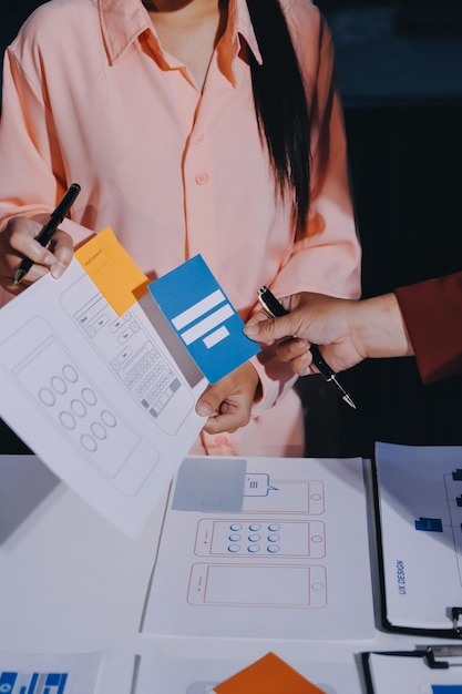 Joven equipo creativo de negocios asiáticos trabajan juntos proyecto de diseño de software de aplicaciones móviles reunión de tormenta de ideas tecnología de Internet teléfono inteligente diseñador de aplicaciones web oficina compañero de trabajo concepto de trabajo en equipo